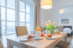 Tisch mit 6 Stühlen und Blick in das kleinere Schlafzimmer
